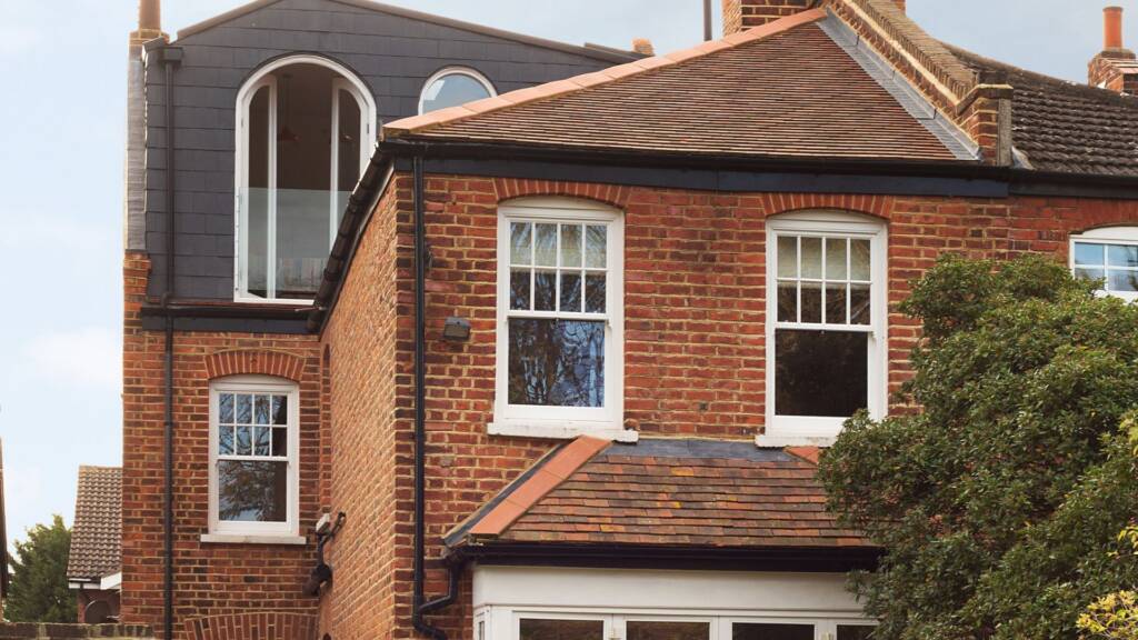 close up of skyscape with arch window roof loft extension blending in with the red brick exterior