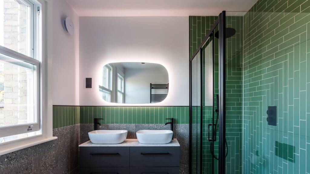 A striking green accent wall and complementary tiles create a bold, modern oasis.