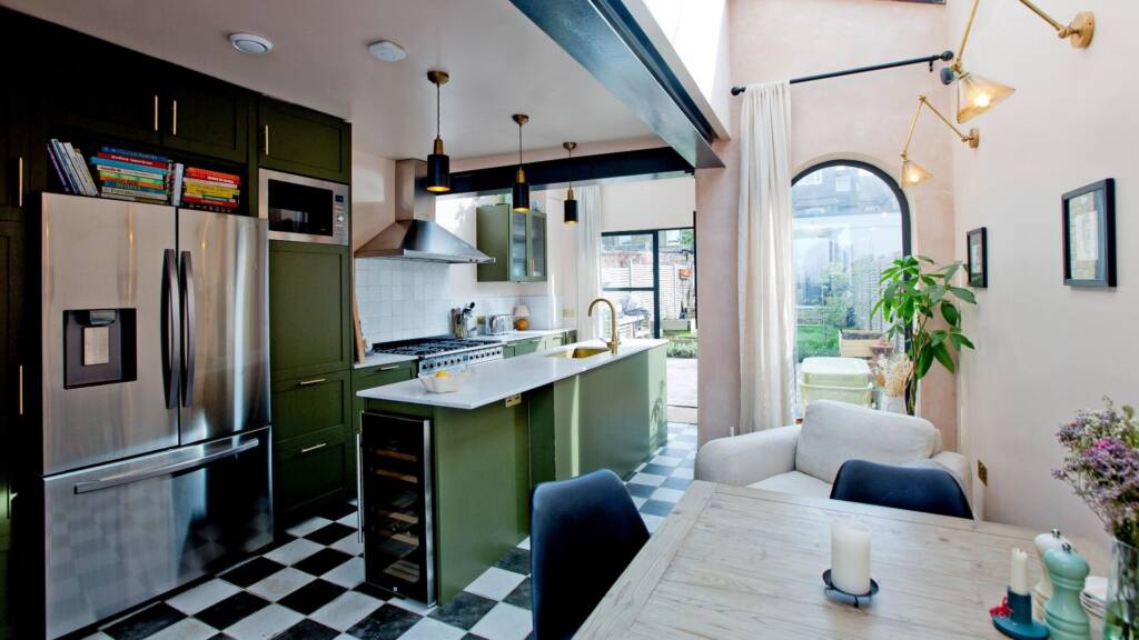 Rear view of a kitchen showing arched shapes flowing from one room to another, with dark cabinetry and natural light.
