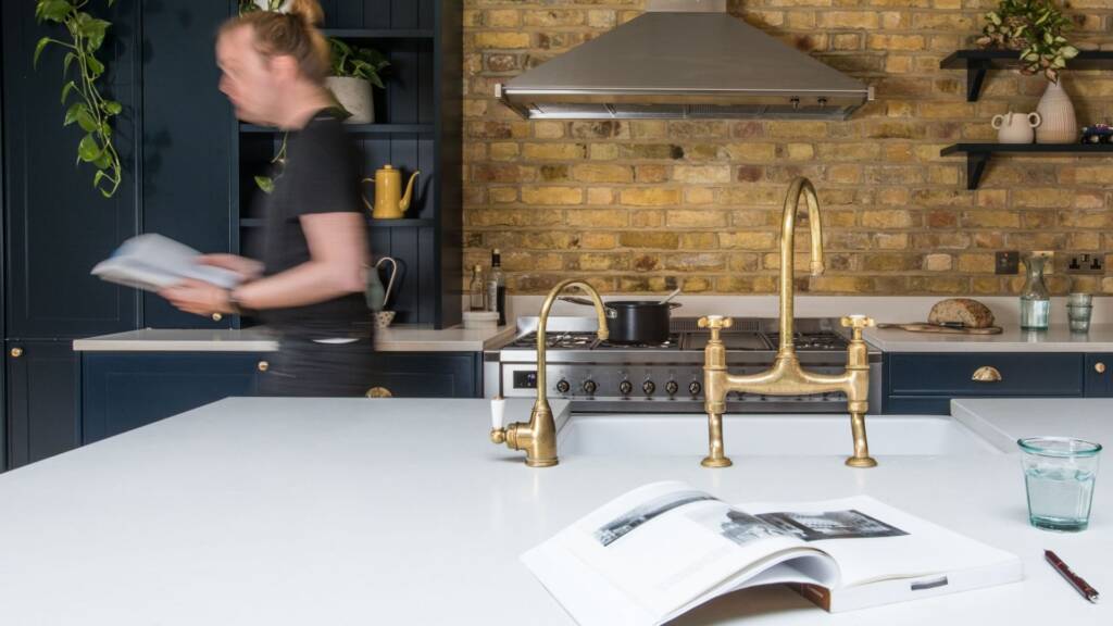 Kitchen island with sink and gold Victorian taps under industrial lighting