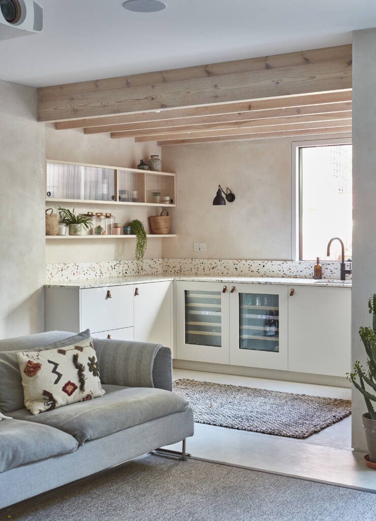 A basement family room with a kitchenette, a polished concrete floor, and a 'fin-like' ceiling detail.