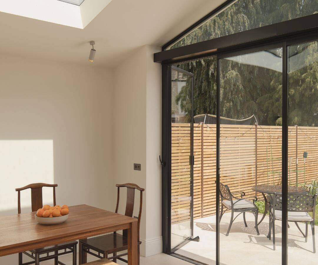 High end slide and turn glass doors fully open to connect a modern London kitchen extension directly with the garden.