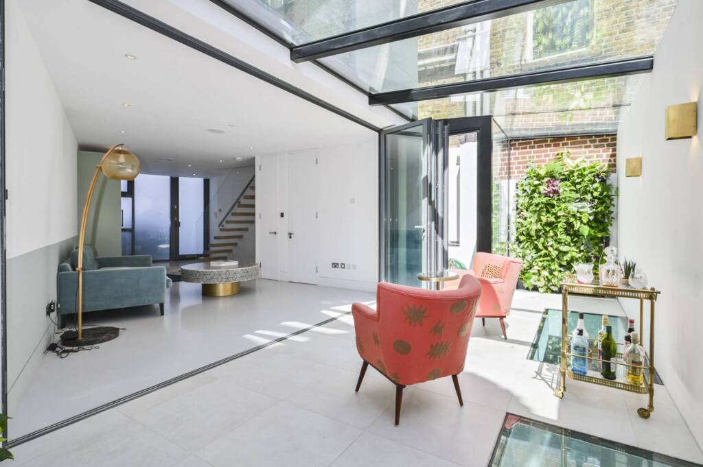 The living wall runs alongside the bi-fold doors, softening the transition between the glass extension and the garden beyond.